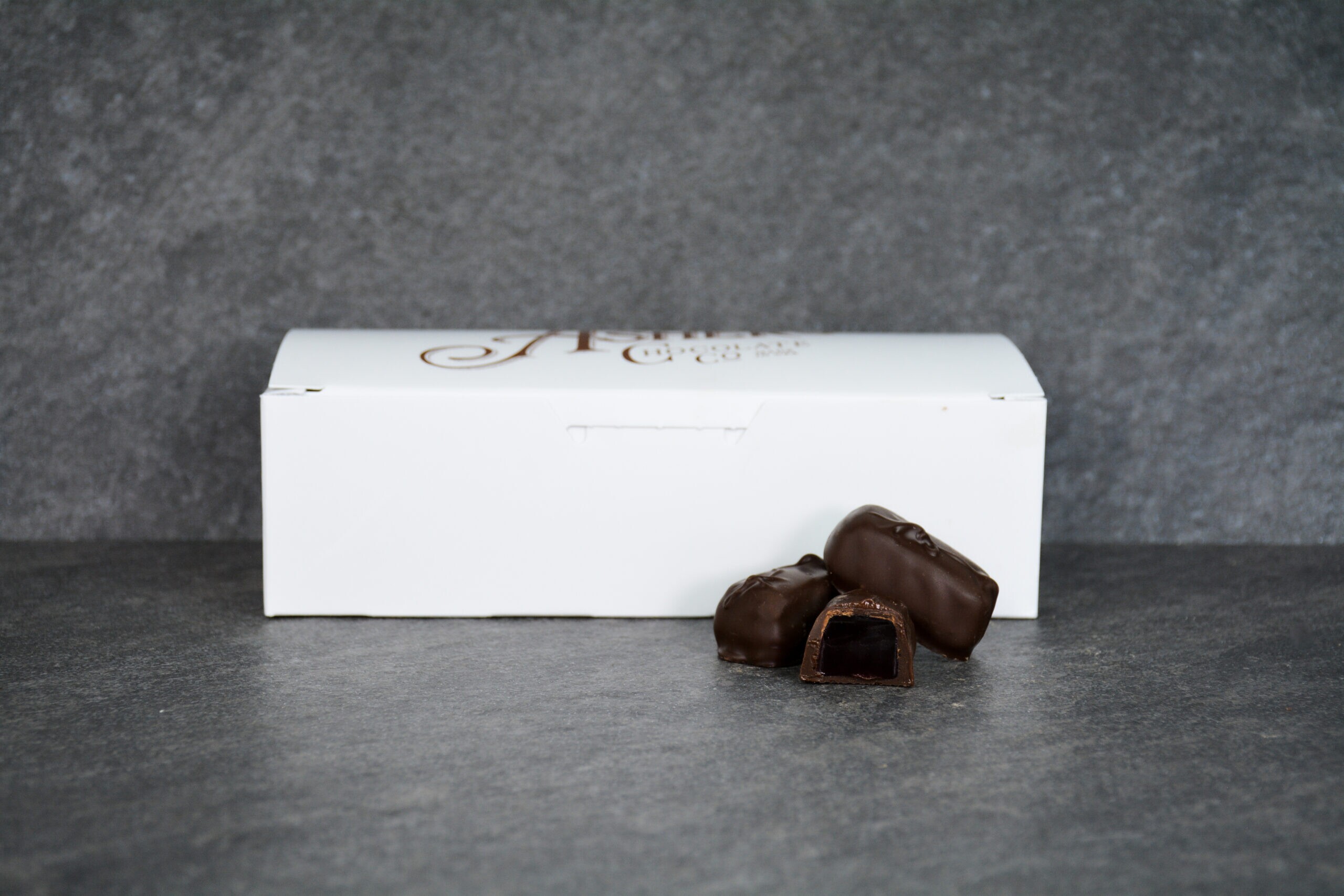 Dark chocolate raspberry jellies displayed in front of a small white box.