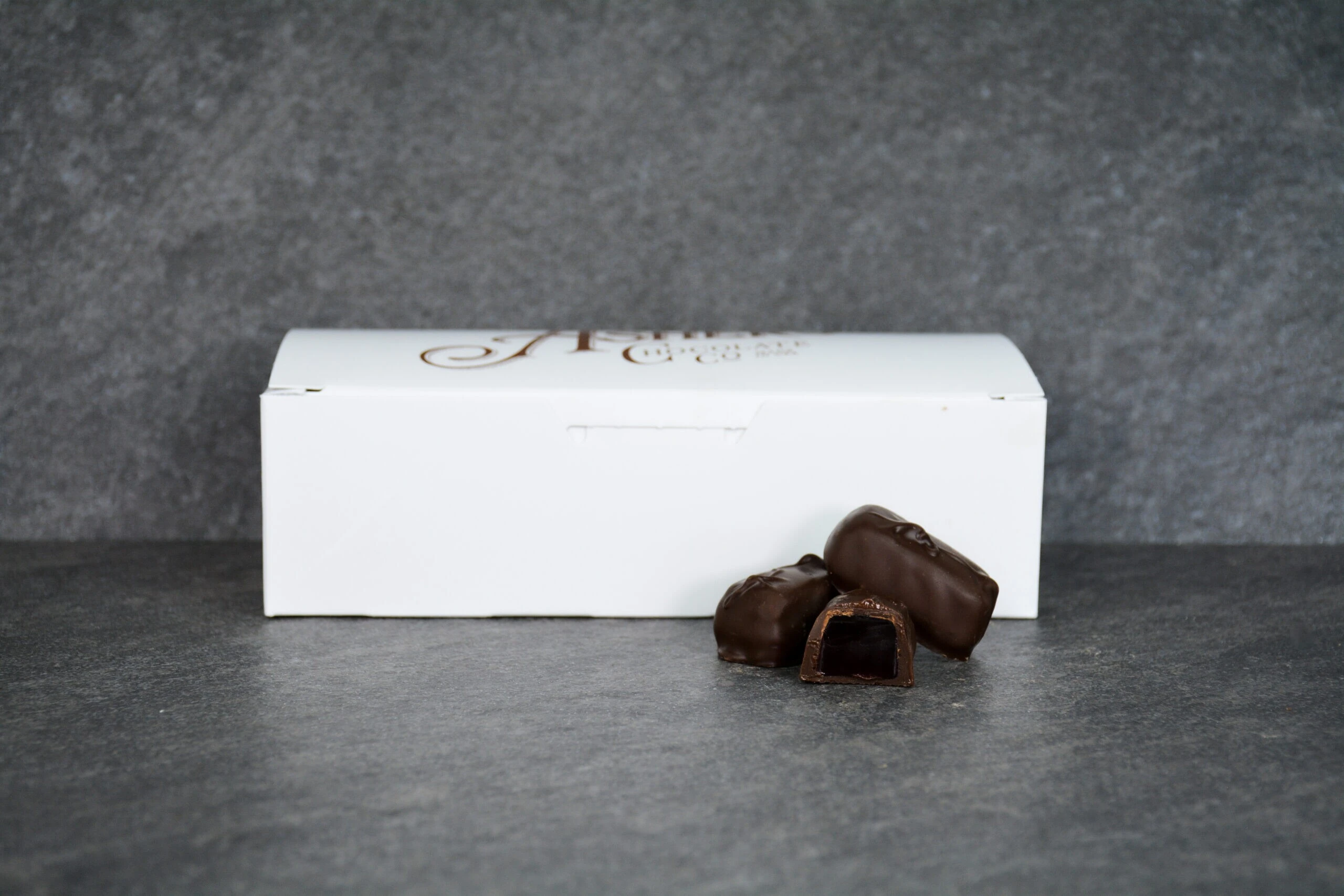 Dark chocolate raspberry jellies displayed in front of a small white box.