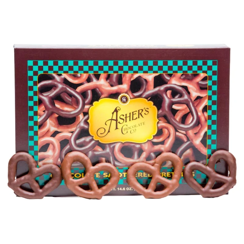 A box of Assorted Chocolate Pretzels-Milk and Dark Chocolate is shown with four chocolate-covered pretzels displayed in front. The box features images of additional pretzels and a yellow label in the center.