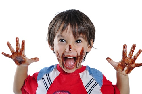 kid with melted chocolate on hands and face