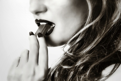 black and white photo of woman tasting chocolate seductively