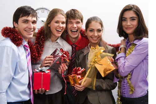 festive group of young employees smiling and holding corporate gifts