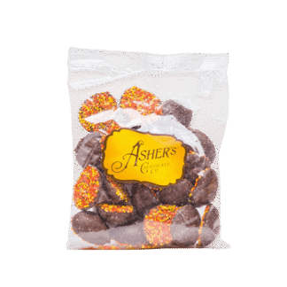 A clear 4 oz bag labeled Milk Chocolate Fall Nonpareils contains round milk chocolate candies from Ashers Chocolate Co., each topped with festive red, yellow, and orange sprinkles.
