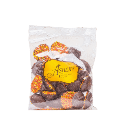 A clear 4 oz bag labeled Milk Chocolate Fall Nonpareils contains round milk chocolate candies from Ashers Chocolate Co., each topped with festive red, yellow, and orange sprinkles.