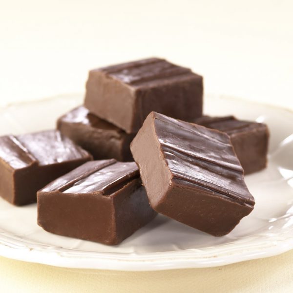 Chocolate Fudge squares piled on a white plate.
