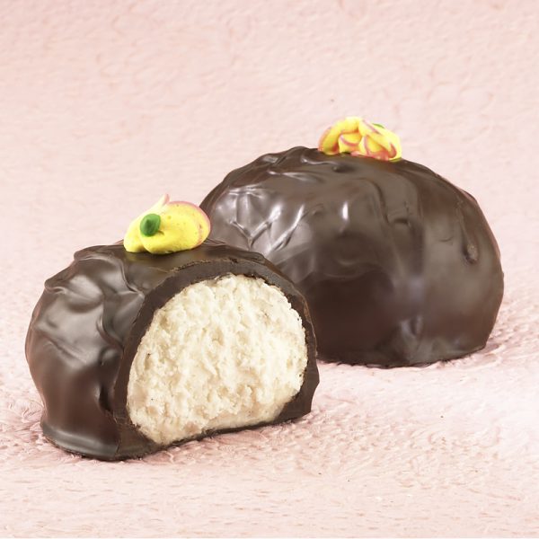 16-oz Dark Chocolate Coconut Cream Eggs with edible yellow decorative flowers on top. One (1) Egg cut in half to reveal white inside. Other egg whole in background. Pictured on light purple backdrop.
