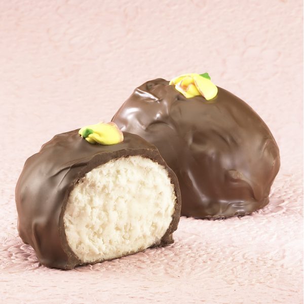 16-oz Milk Chocolate Coconut Cream Eggs with edible yellow decorative flowers on top. One (1) Egg cut in half to reveal white inside. Other egg whole in background. Pictured on light purple backdrop.