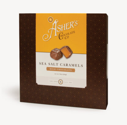 Milk Chocolate Sea Salt Caramels Traditional Box with yellow and white Asher's Chocolate Co. Label. Two (2) caramels on the front of the box reveal, color, size, shape, and texture of candies. Displayed on white background.