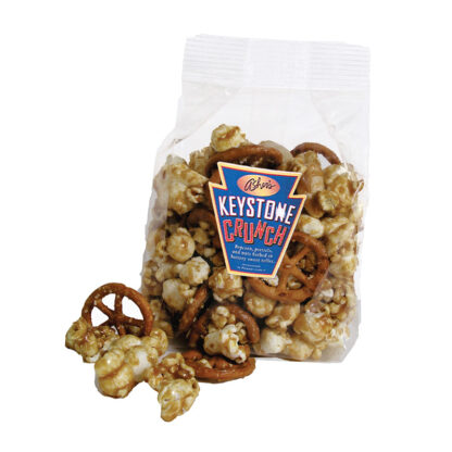 Keystone Crunch clear bag shown on white background. Pieces of pinwheel pretzels, and caramel popcorn lie outside of the bag.