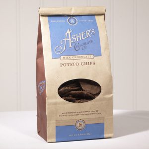 Milk Chocolate Potato Chip Coffee Bag. Coffee Bag is brown with blue details. Clear plastic circular window on front displays Milk Chocolate Potato Chips inside. Shown on white background.