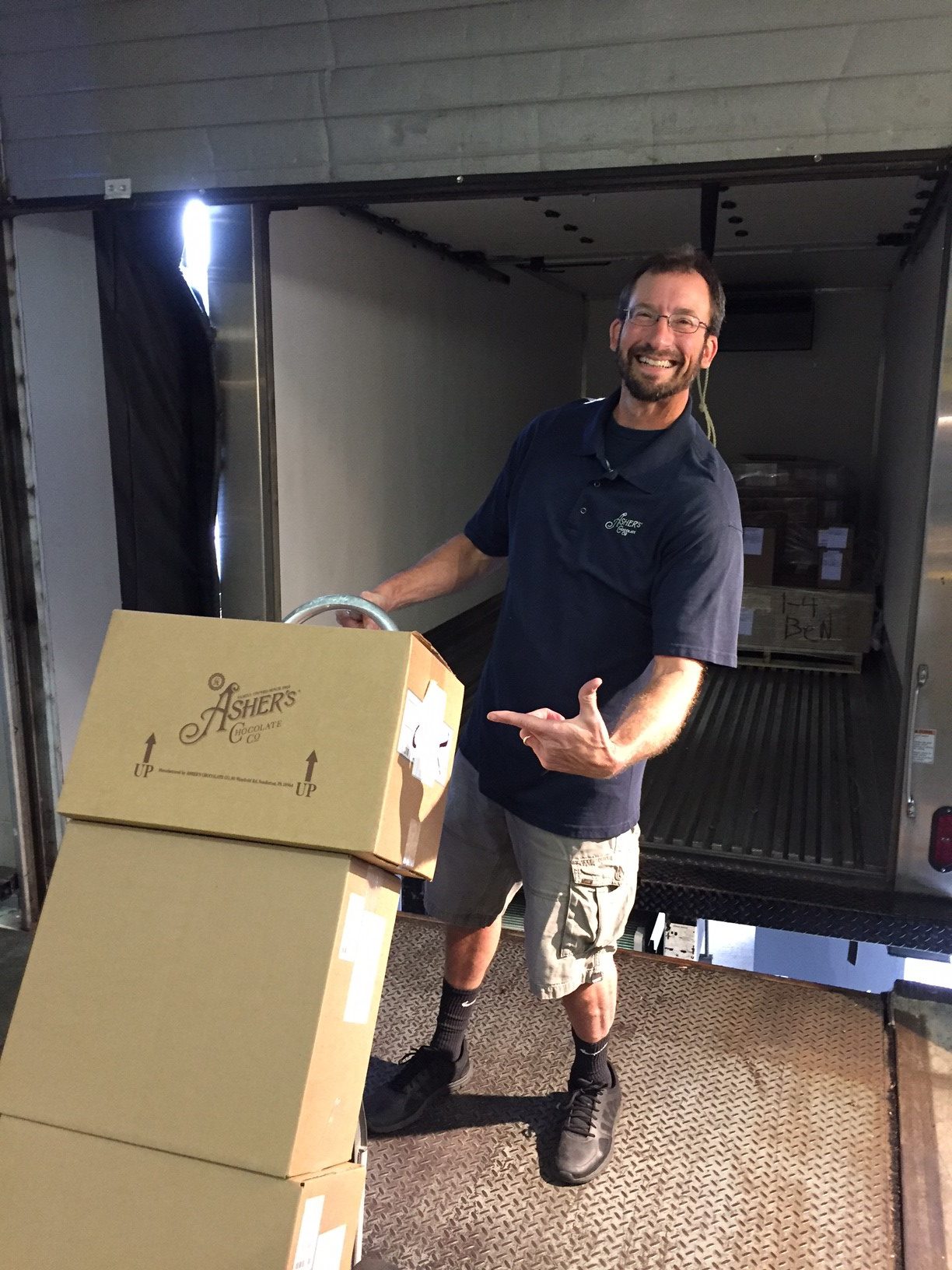 Asher's Chocolate Co. employee highlight and delivery driver, Ben Gossard, unloading a stack of boxes for an Asher's delivery.