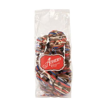 A clear bag of chocolate-covered pretzels drizzled with red, white, and blue, labeled Ashers Chocolate Co. on a red logo.