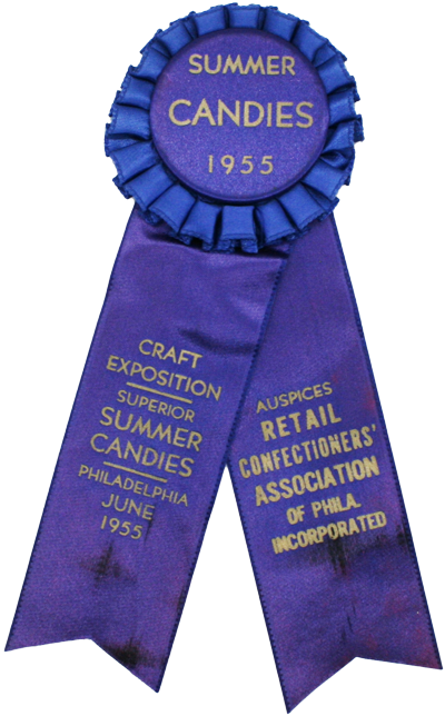 A blue ribbon with gold text reads: SUMMER CANDIES 1955, CRAFT EXPOSITION, SUPERIOR SUMMER CANDIES, PHILADELPHIA JUNE 1955, RETAIL CONFECTIONERS ASSOCIATION OF PHILA INCORPORATED—a delightful nod to Asher’s chocolate history and the celebrated traditions of fine confectionery.