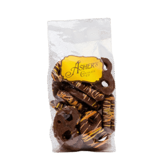 A clear bag of chocolate-covered pretzels with yellow drizzle, labeled Ashers Chocolate Co. on a yellow tag, set against a white background.