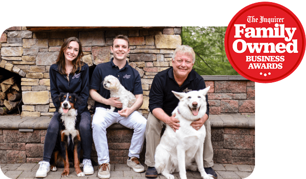 Asher family sitting on a stone ledge, each with a dog, with an Inquirer Family Owned Business Awards logo in the corner.